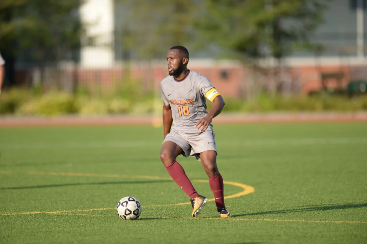 Jean-Luc wearing the captain's armband, dribbling during a Brooklyn College soccer match